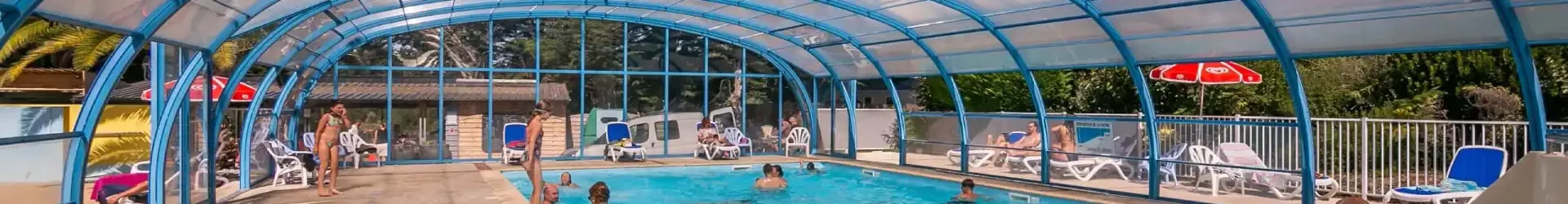 Piscine intérieure chauffée et couverte sous une verrière lumineuse au camping dans le Morbihan.