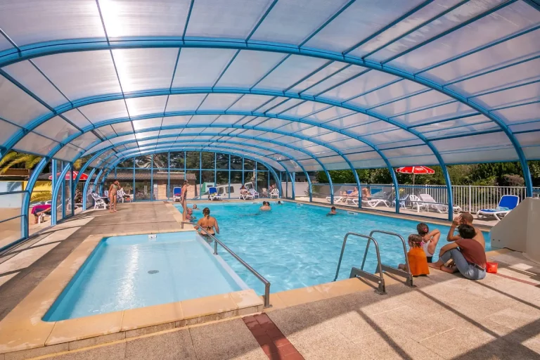 Piscine intérieure chauffée et couverte sous une verrière lumineuse au camping dans le Morbihan.